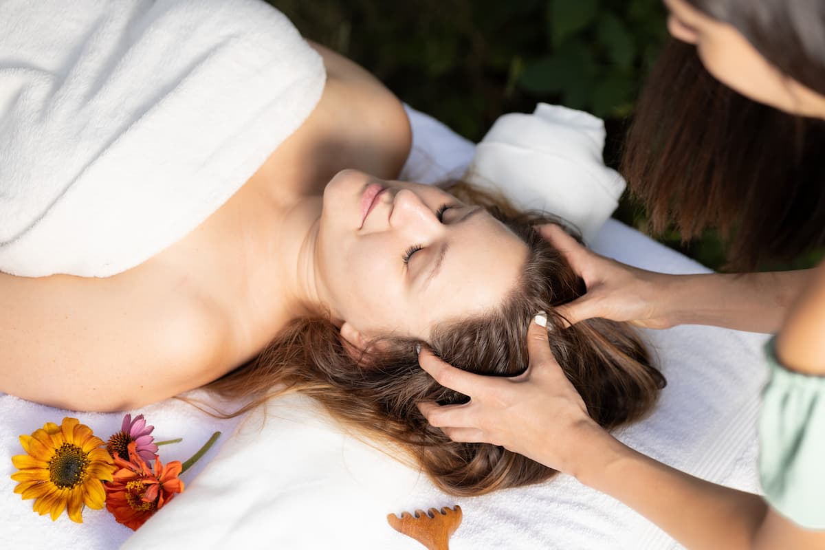 A képen egy nő fejét maszírozzák, kényelmes pózban