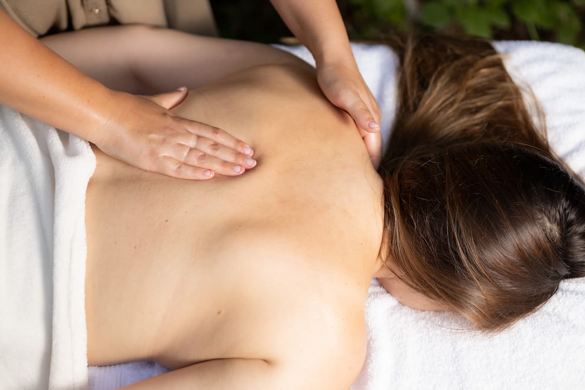 A képen egy páciens hátát maszírozza a masszőr